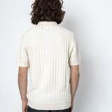 Person wearing a white ribbed knit polo shirt against a plain background
