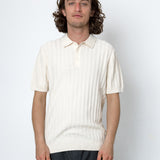Man wearing a cream-colored knit polo shirt against a white background