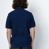 Person wearing a navy blue polo shirt against a white background