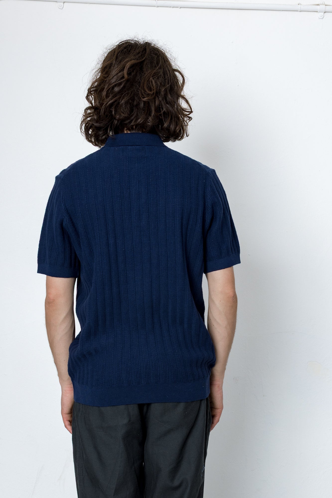 Person wearing a navy blue polo shirt against a white background