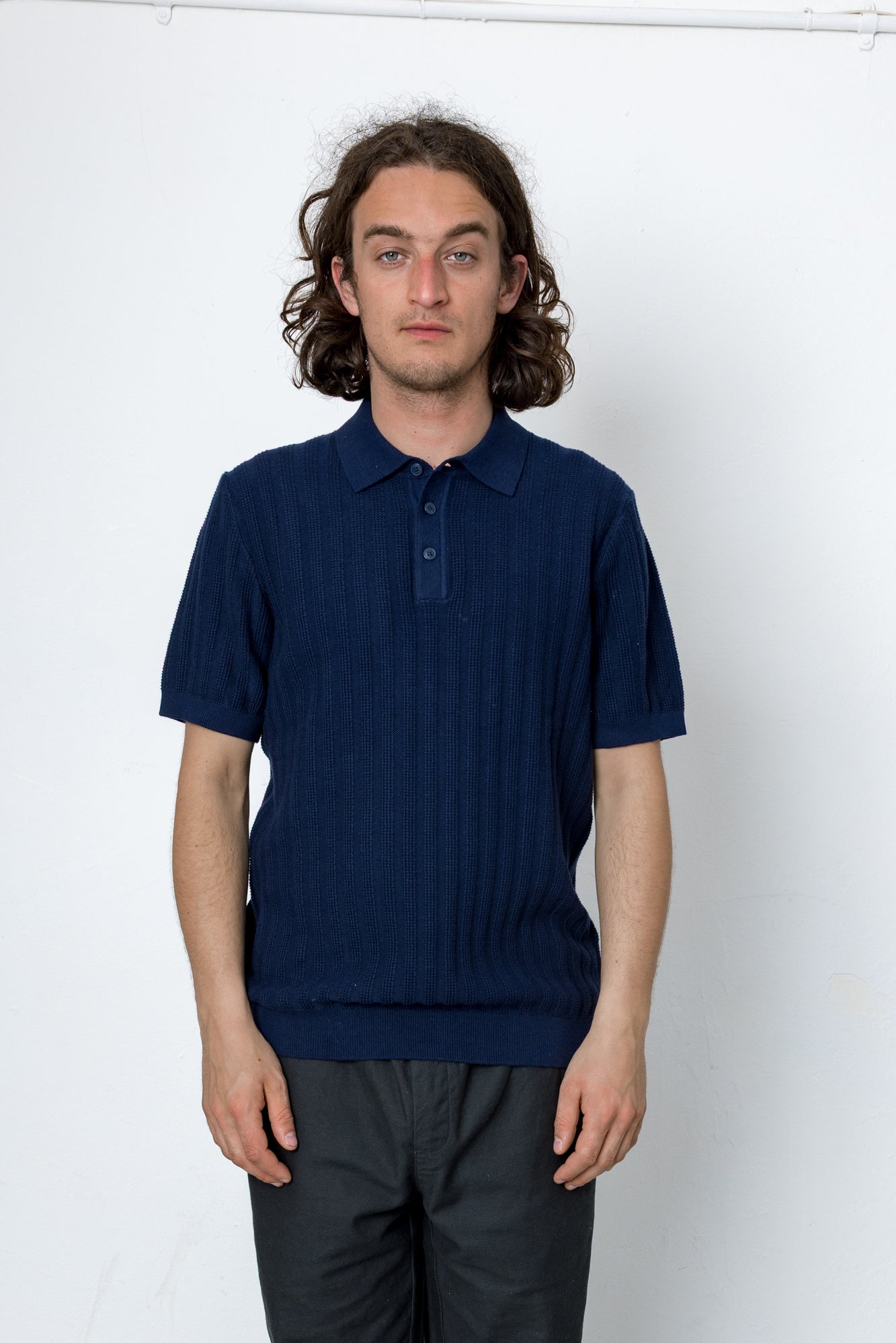 Man wearing a navy blue polo shirt against a white background