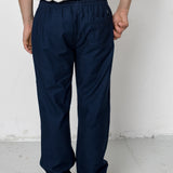 Person wearing navy pants and a white shirt against a plain background