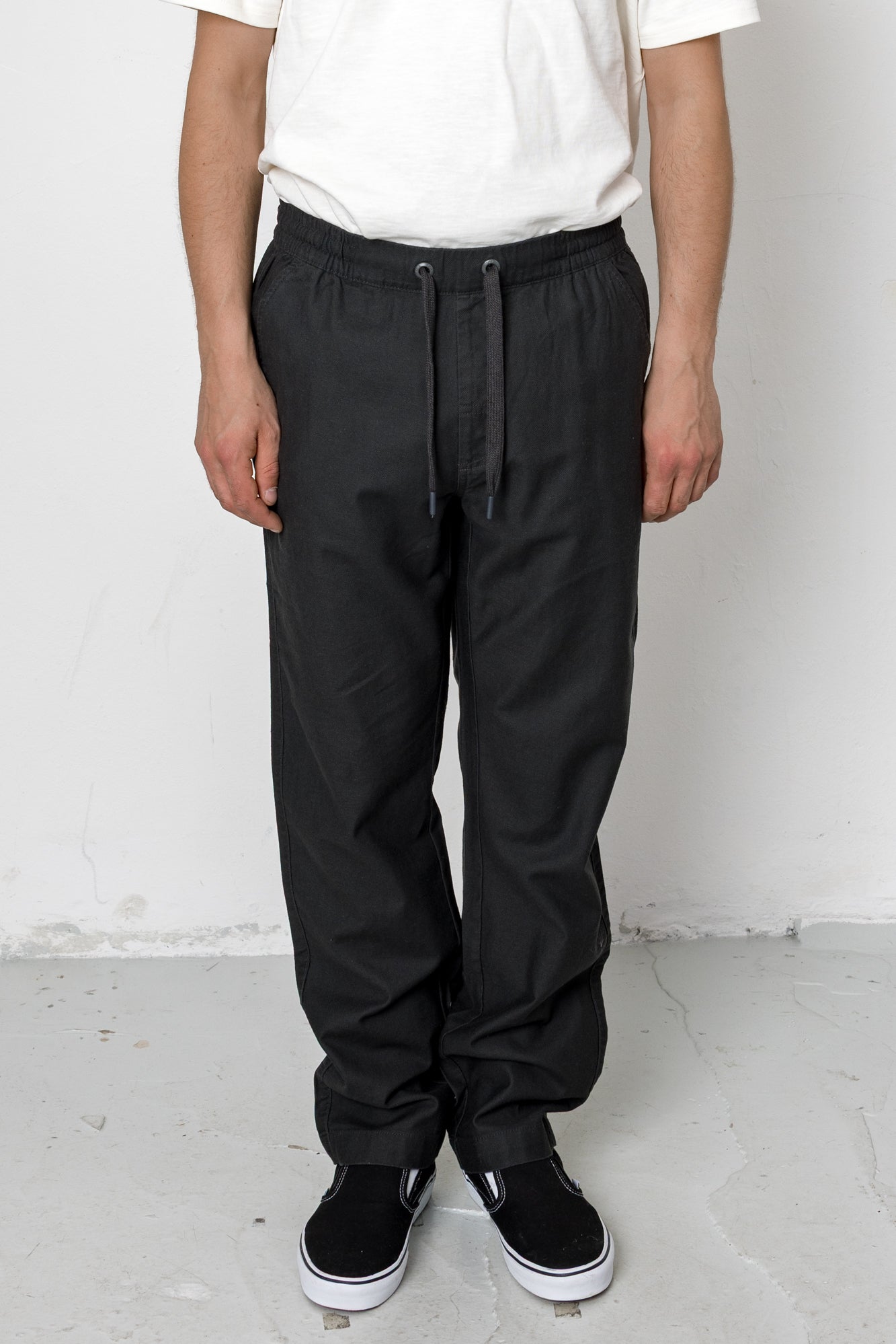 Person wearing black pants and a white shirt against a white background