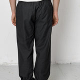 Person wearing black pants and a white shirt against a plain background