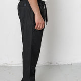 Person wearing black pants and white shoes against a plain background