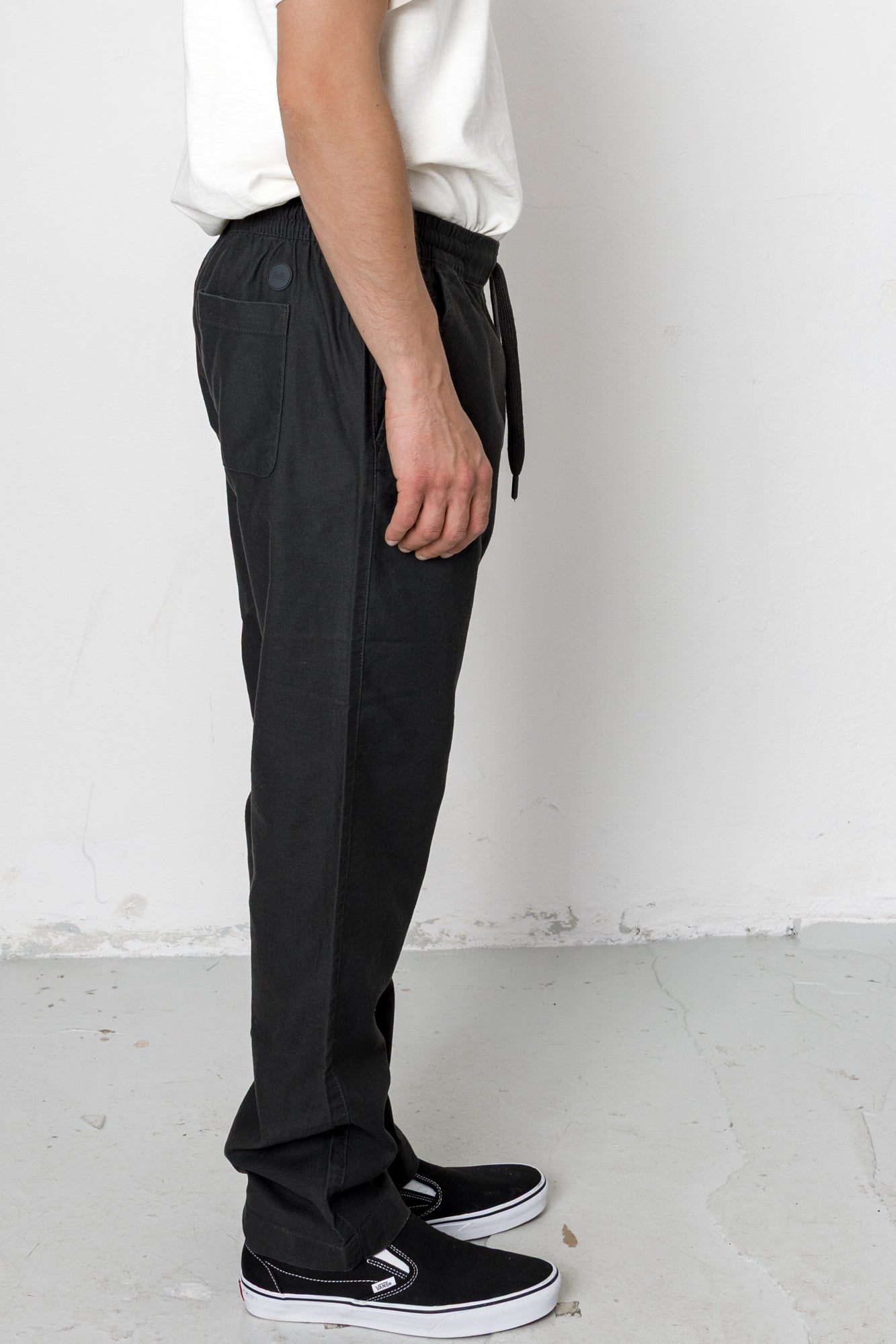 Person wearing black pants and white shoes against a plain background
