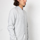 Man wearing a light gray zip-up hoodie against a white background