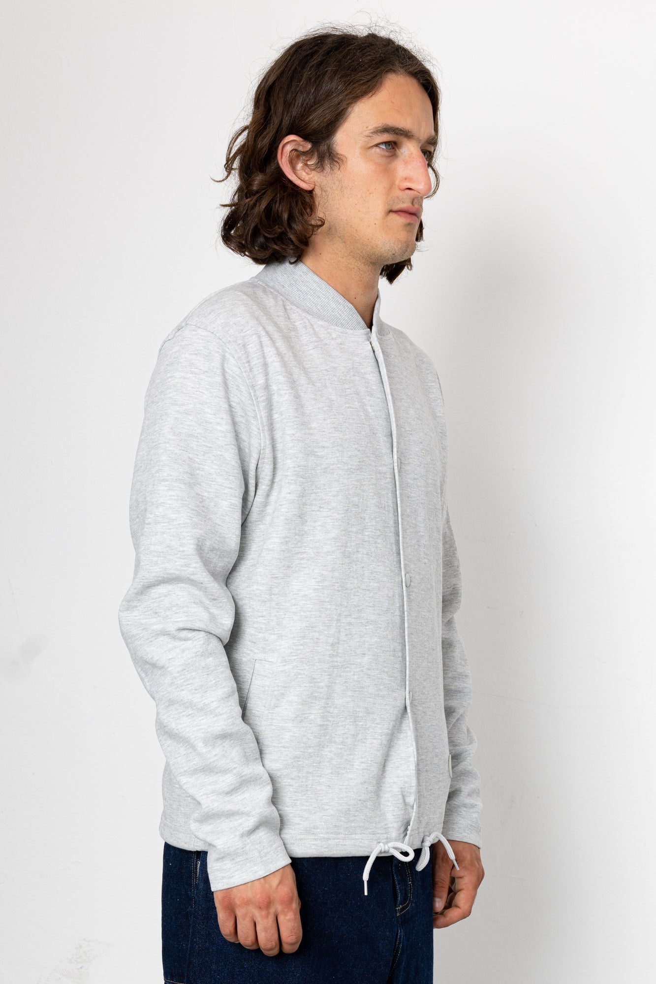 Man wearing a light gray zip-up hoodie against a white background