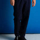 man wearing navy trousers and bright blue t-shirt, standing against a bright blue background