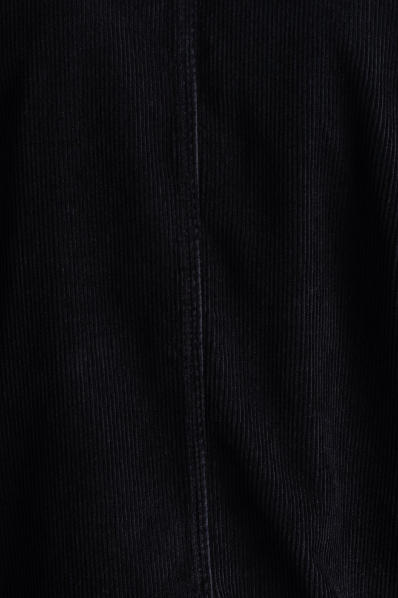 Close-up of dark navy corduroy fabric with a vertical ribbed texture and a central seam.