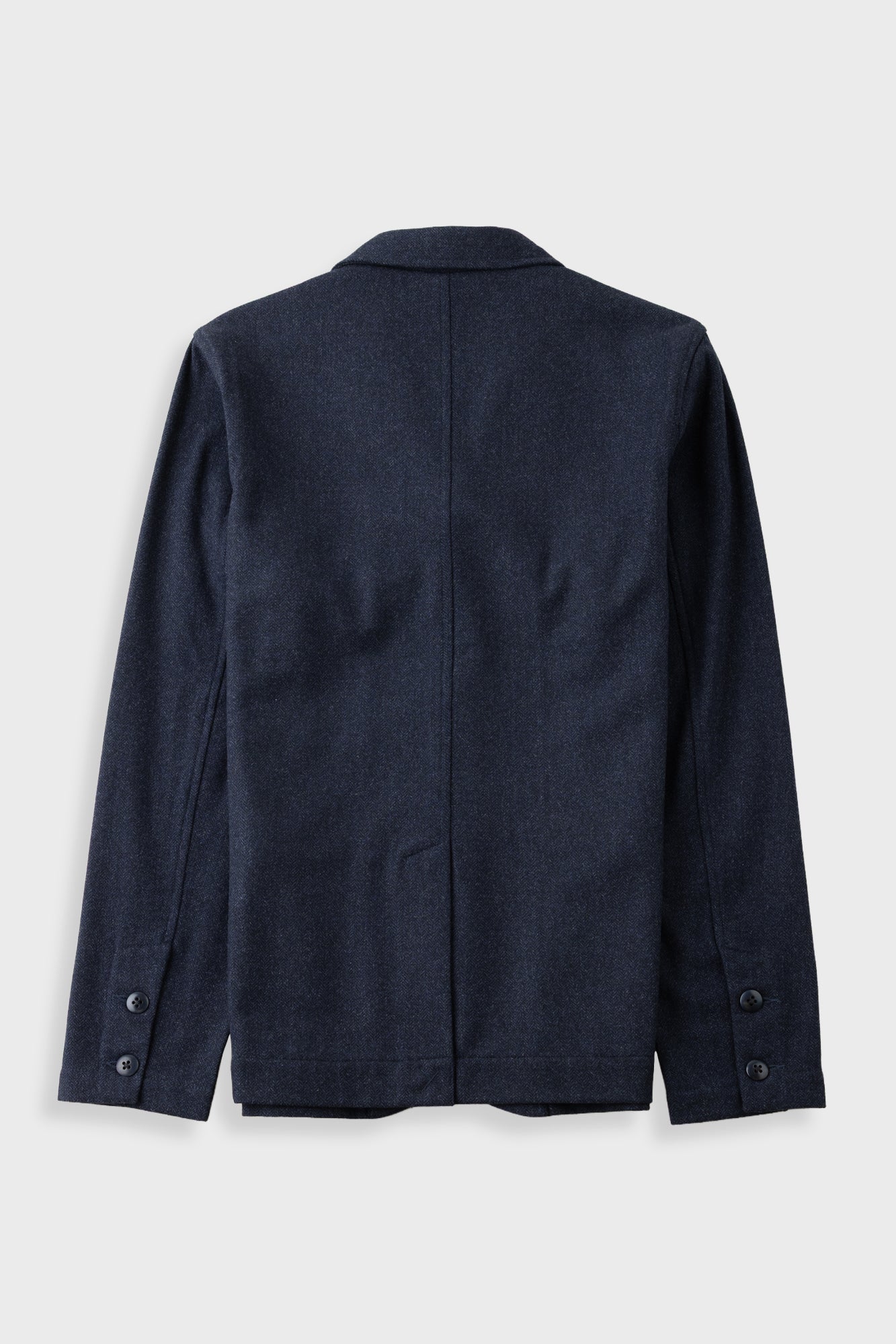 A dark navy blue blazer shown from the back, featuring a clean silhouette with buttoned cuffs and a central seam, photographed against a light gray background.