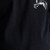 Close-up of a dark navy blue fabric with a small white embroidered graphic of a rider on a horse on the chest.