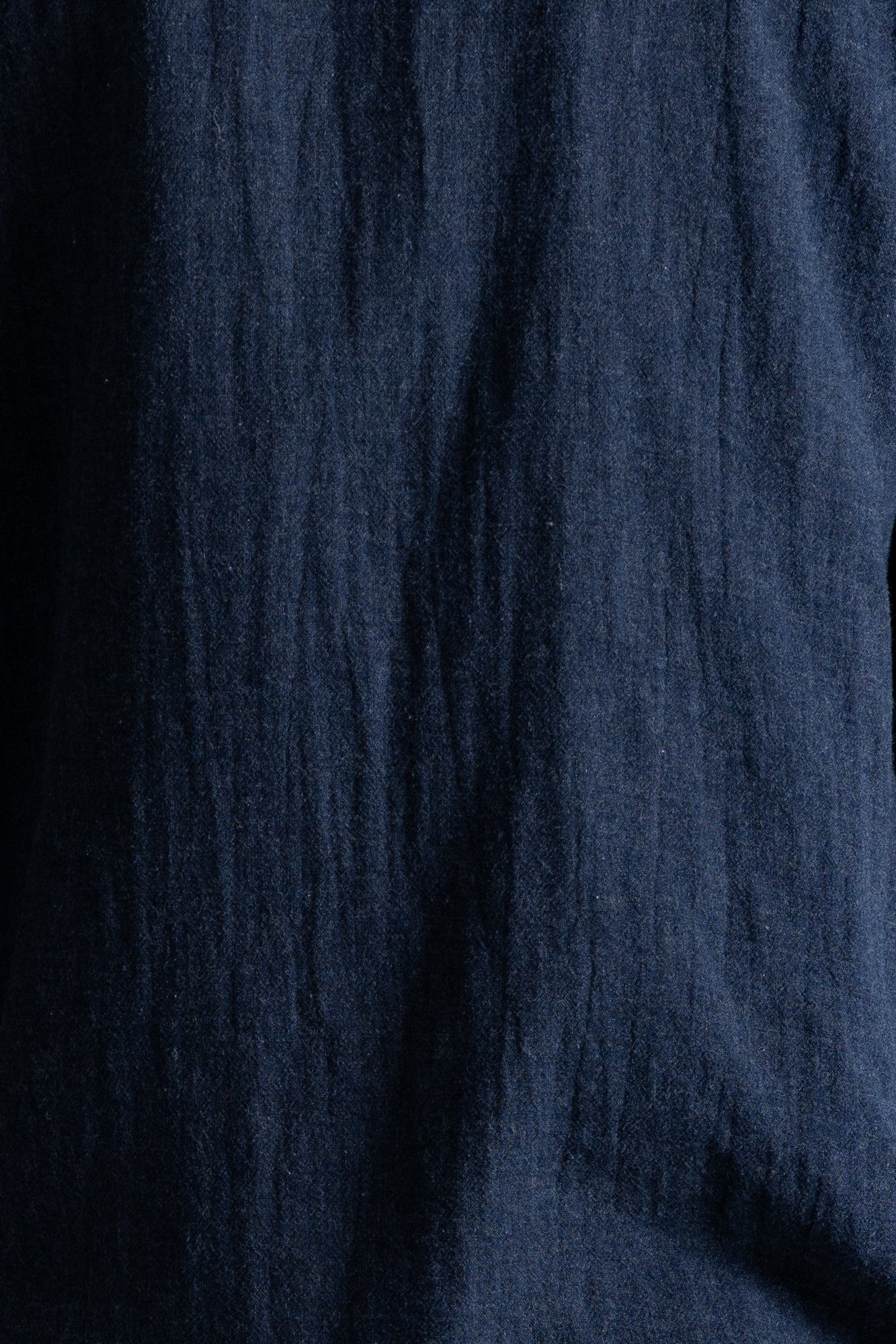 A close-up of dark navy blue textured fabric with a crinkled linen-like weave.