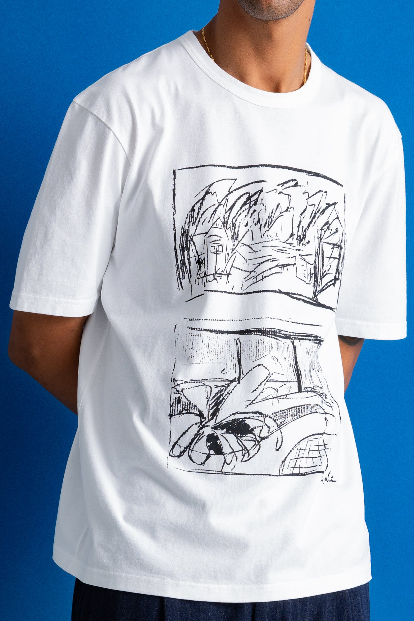 A man wearing a white short-sleeve t-shirt with a black line art graphic print on the front, set against a solid blue background.