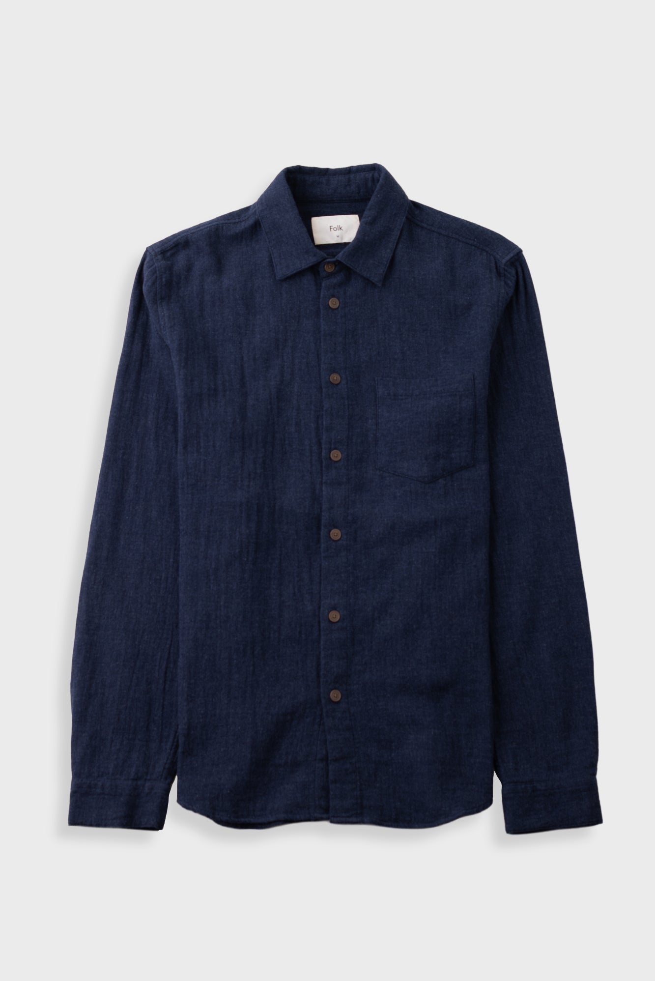 Dark navy button up shirt laid against a grey backdrop
