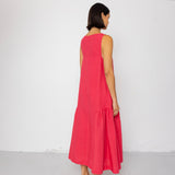Woman wearing a pink dress standing against a white wall
