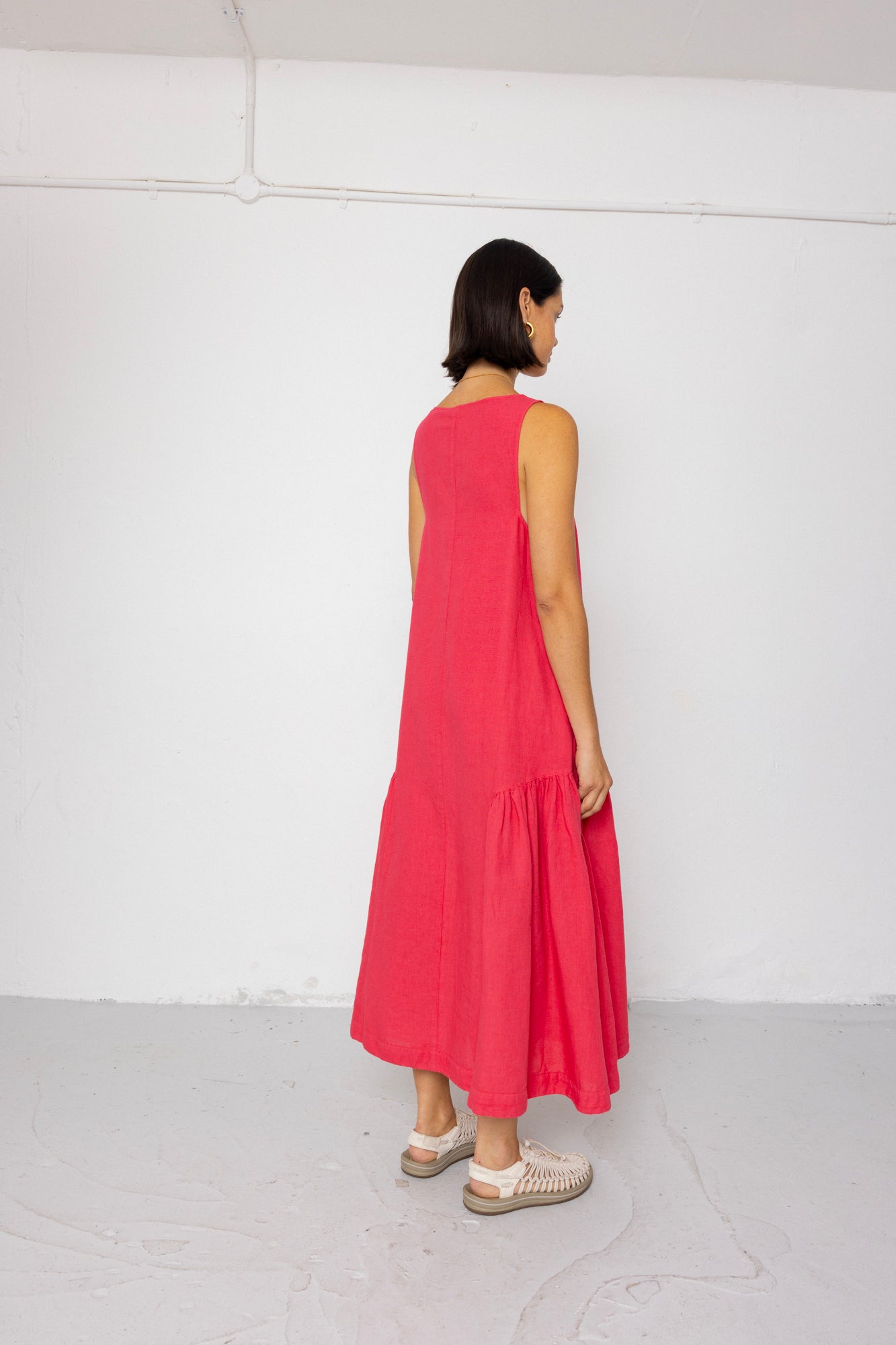 Woman wearing a pink dress standing against a white wall