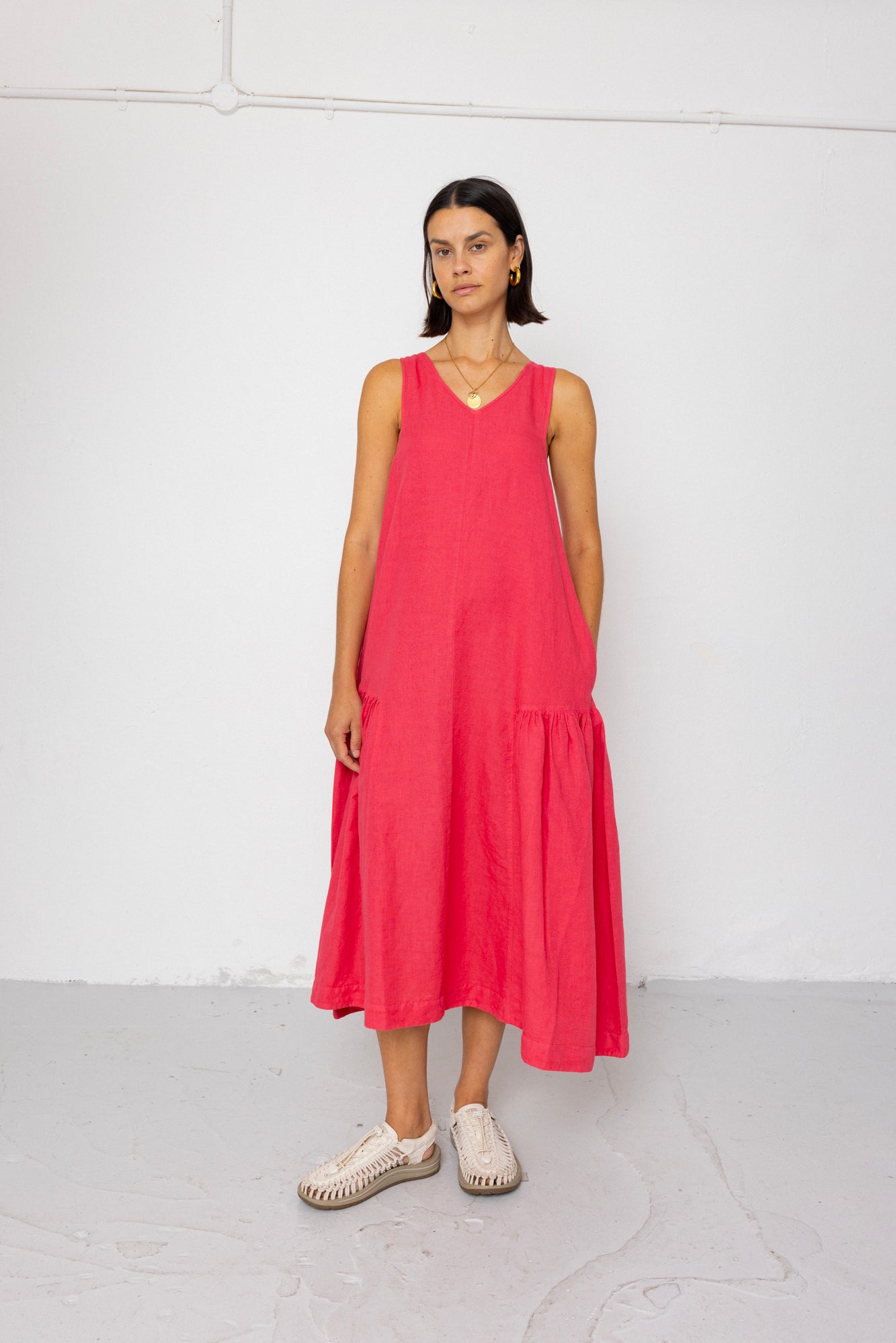 Woman wearing a pink sleeveless dress against a white background