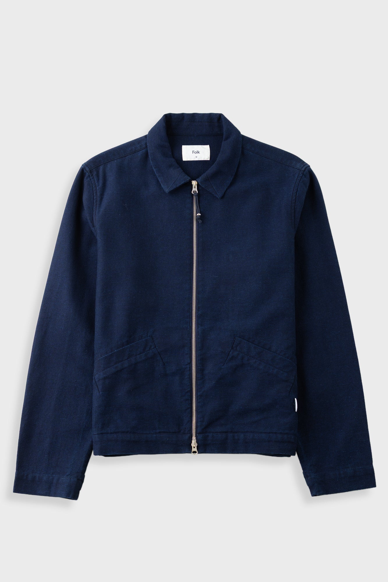 A dark navy blue zip-up jacket with a pointed collar and front pockets, displayed flat against a light gray background.