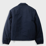 A dark navy blue jacket shown from the back, featuring a classic collar, long sleeves, and elasticized cuffs, photographed against a light gray background.