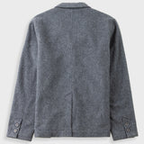 A gray textured wool-blend jacket shown from the back, featuring a classic collar, long sleeves with buttoned cuffs, and a central seam running down the back, photographed on a light gray background.
