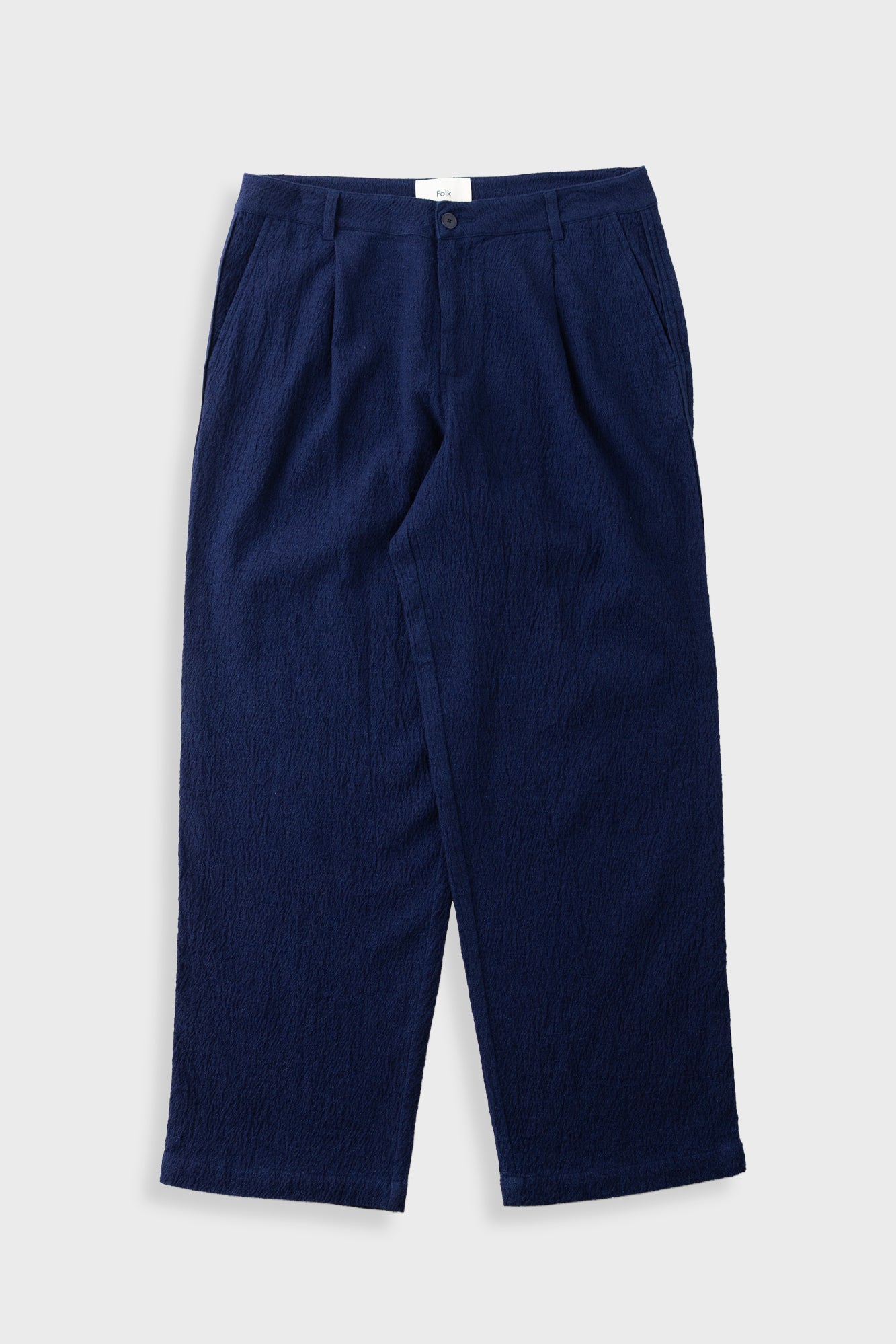 A pair of dark navy blue cropped trousers with a textured crinkle fabric, shown flat against a light gray background.