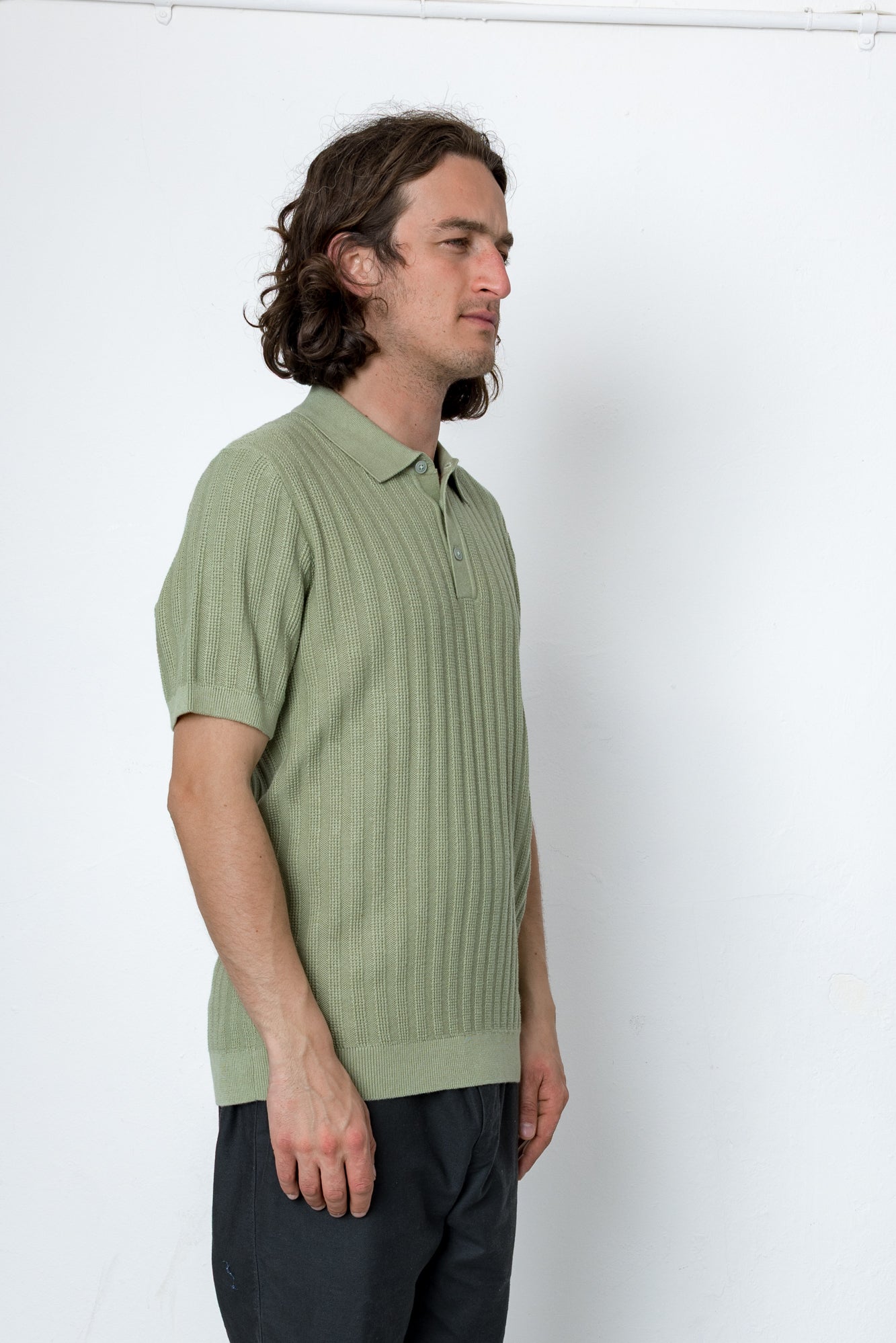 Man wearing a green ribbed knit polo shirt against a white background