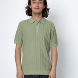 Man wearing a light green polo shirt against a white background