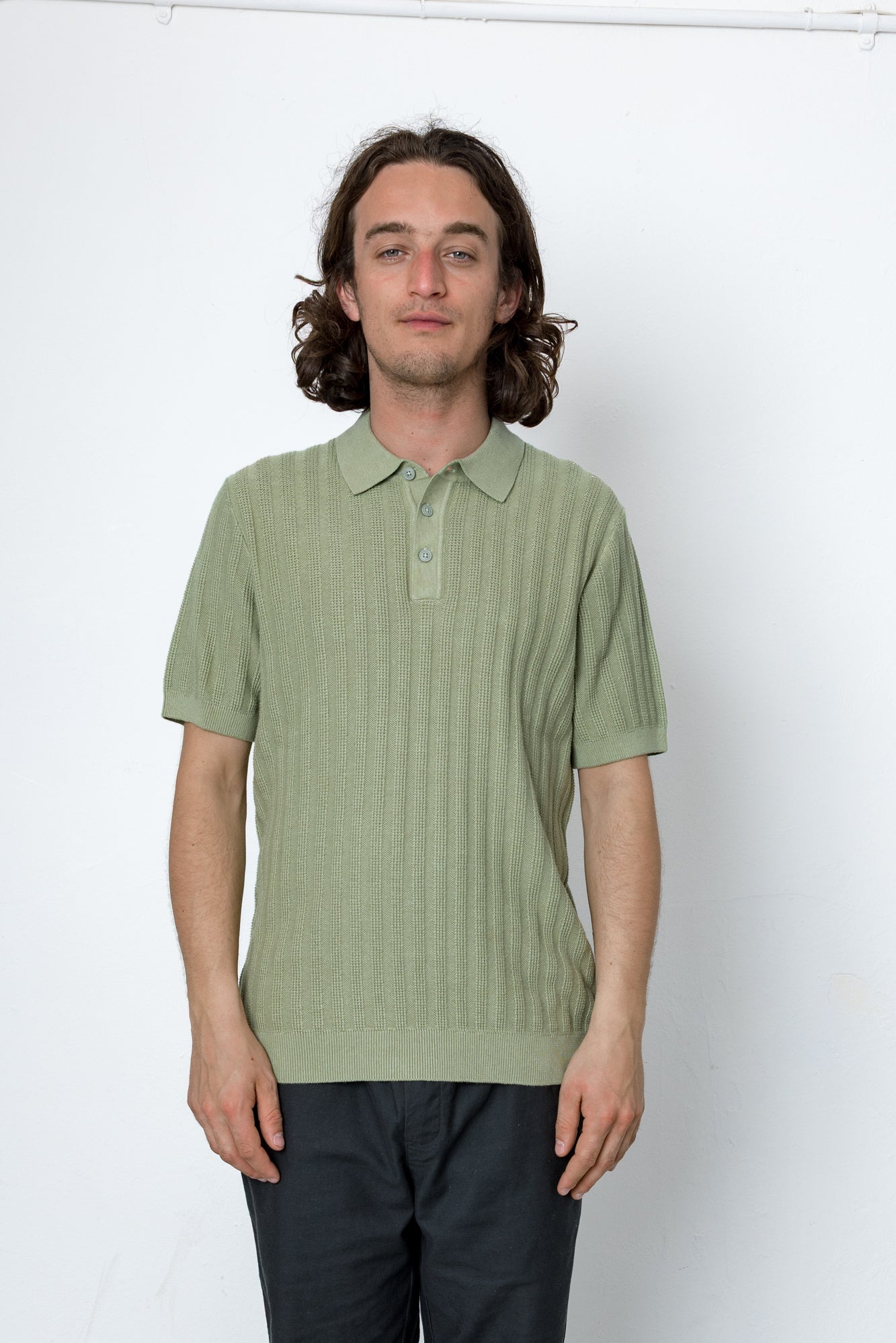 Man wearing a light green polo shirt against a white background